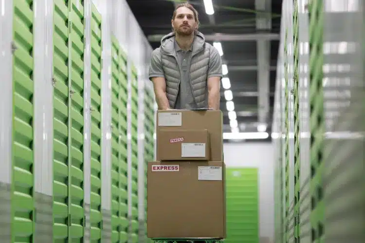 A man pushing a cart loaded with stacked cardboard boxes through.