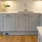 A clean modern kitchen with a subtle roach silhouette near a baseboard.